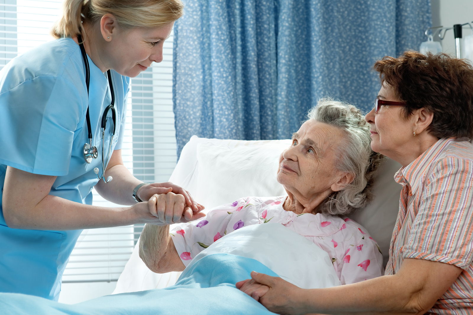 old lady lying in bed, with relative and nurse